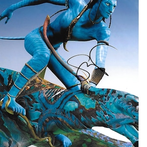 Könnte beinhalten: Ein blauhäutiger Außerirdischer mit langen schwarzen Haaren und blauen Augen reitet auf einem großen, blauen, reptilienartigen Wesen. Der Außerirdische trägt einen braunen Ledergurt um die Taille und einen braunen Ledergurt am linken Arm. Der Außerirdische hält sich mit seiner rechten Hand am Rücken des Wesens fest. Das Wesen hat einen langen, spitzen Schwanz und einen großen, offenen Mund. Die Unterschrift des Außerirdischen ist in der unteren rechten Ecke des Bildes zu sehen.