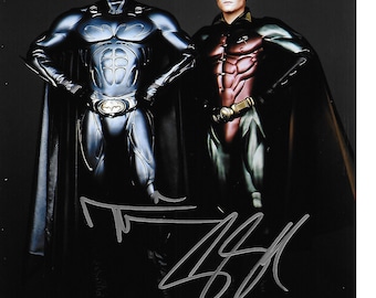 May include: A black and blue Batman costume and a red and green Robin costume. The costumes are worn by two figures standing side by side. The figures are posed in a heroic stance. The image is signed with a silver signature.