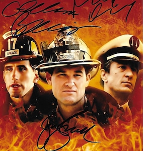 Peut inclure: Photo promotionnelle de trois hommes portant des casques de pompiers, sur fond de flammes. Les casques affichent le mot "Chicago" et le numéro "17". L'image est autographiée à l'encre noire.