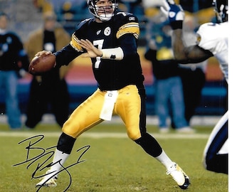 May include: A black and yellow football jersey with the number 7 on the front. The jersey is signed by Ben Roethlisberger.