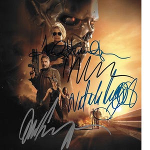 May include: A movie poster featuring the Terminator skull and several actors with guns. The poster has multiple signatures in blue and silver ink. The background is a fiery orange and yellow.