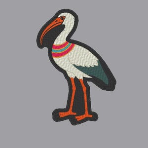 May include: Embroidered patch featuring a stylized white ibis bird with orange legs and beak. The bird has a black outline and a colorful striped collar in shades of red, teal, and yellow. The patch is on a gray background.