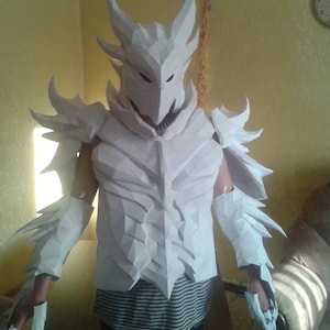 May include: White papercraft dragon armour costume with a helmet and gauntlets.