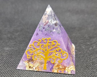 May include: A pyramid-shaped object made of translucent purple resin with a gold-colored tree silhouette on the front face. The interior contains embedded metallic gold flakes and dark purple crystalline fragments visible through the clear resin structure.