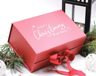 May include: A red gift box with a white ribbon and the text "Aria's Christmas Eve box." The box is decorated with white stars.