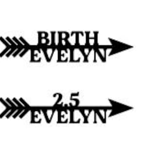 Puede incluir: Cartel de madera negro en forma de flecha con el nombre "EVELYN" y la palabra "BIRTH" encima. Un segundo cartel muestra "EVELYN" con el número "2.5". Los carteles son decorativos.
