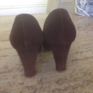 May include: A pair of brown suede heeled shoes with a block heel.