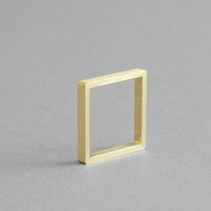 Può includere: Un semplice anello quadrato in oro con una finitura liscia e lucida.