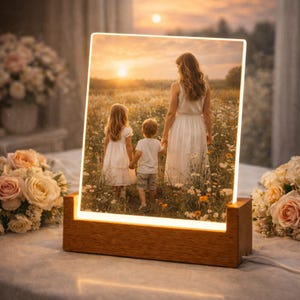 May include: A lighted photo display featuring a family in a field of flowers at sunset. The rectangular photo is set in a wooden base with a warm glow. The image shows a mother and two children walking away from the viewer.