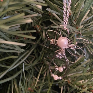 Close up view of 1.5-inch Handcrafted Silver Wire Angel Necklace - accented with silver and white beads. Elegant Heavenly Charm - Unique Gift for Her