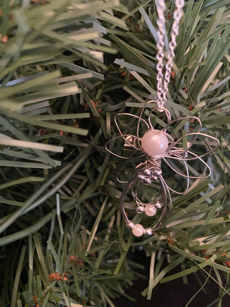 Close up view of 1.5-inch Handcrafted Silver Wire Angel Necklace - accented with silver and white beads. Elegant Heavenly Charm - Unique Gift for Her