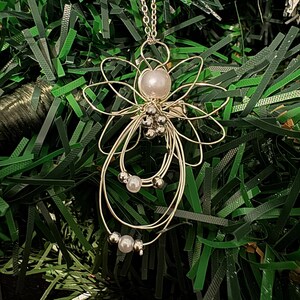 Very close view of 1.5-inch Handcrafted Silver Wire Angel Necklace - accented with silver and white beads. Elegant Heavenly Charm - Unique Gift for Her