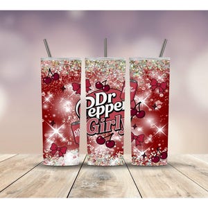 May include: Three stainless steel tumblers with straws, featuring a red and white design with the text "Dr Pepper Girly". The design includes cherries, bows, and sparkling accents. The tumblers are cylindrical and sit on a wooden surface.