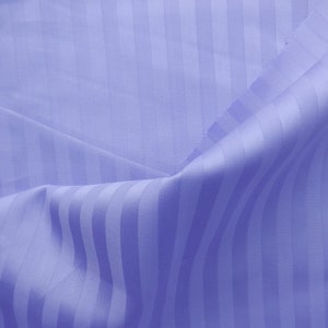 May include: A close-up of a light blue fabric with a striped pattern. The fabric is folded and has a soft, smooth texture.