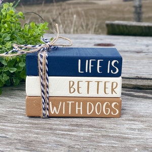May include: A stack of three wooden blocks painted in navy blue, white, and brown. The blocks are tied together with twine and have the words "Life is Better with Dogs" written on them.