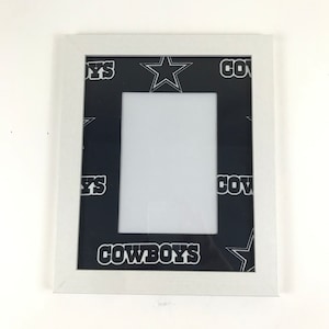 May include: White picture frame with a black and white Cowboys themed mat. The mat has a repeating pattern of stars and the word "Cowboys".