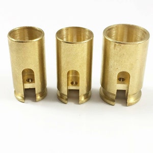 May include: Three gold-colored metal tubes with a cut-out design on the side. The tubes are different sizes.