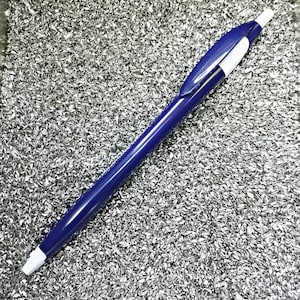 May include: A blue pen with a white top lying on a bed of silver metallic flakes.