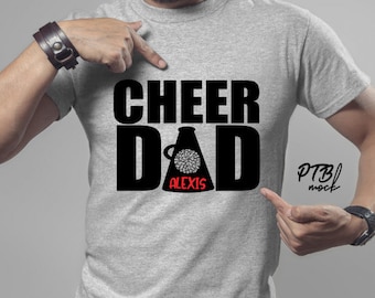 May include: Grey t-shirt with black text that reads "Cheer Dad" with a black megaphone graphic and the name "Alexis" in red text. The text "PTB| mock" is in the bottom right corner.