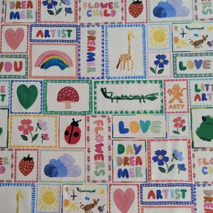 May include: A white fabric with a colorful patchwork design featuring various illustrations and text. The illustrations include a rainbow, a giraffe, a ladybug, a mushroom, a flower, a sun, a heart, a frog, a crocodile, a tiger, a lion, and a cloud. The text includes the words "LOVE", "DAYDREAMER", "ARTIST", "FLOWER CHILD", "LITTLE ART", "ARTY", and "LOVE YOU".
