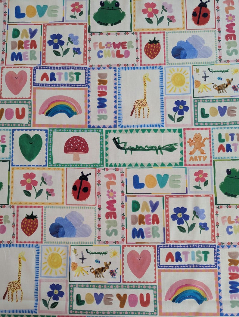 May include: A white fabric with a colorful patchwork design featuring various illustrations and text. The illustrations include a rainbow, a giraffe, a ladybug, a mushroom, a flower, a sun, a heart, a frog, a crocodile, a tiger, a lion, and a cloud. The text includes the words "LOVE", "DAYDREAMER", "ARTIST", "FLOWER CHILD", "LITTLE ART", "ARTY", and "LOVE YOU".