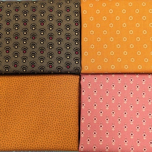 May include: Four folded fabric swatches arranged in a grid. Top left is black with repeating cream and magenta fan patterns. Top right is orange with small cream floral motifs. Bottom left is mustard yellow with tiny brown leaf prints. Bottom right is pink with a repeating cream and maroon diamond pattern.