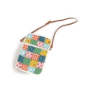 Puede incluir: Un bolso bandolera rectangular con un diseño de patchwork que incluye varios patrones como cuadros vichy rojos, lunares verdes, fresas pequeñas y flores blancas sobre un fondo multicolor, con una correa fina ajustable de color marrón.