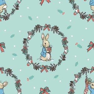 May include: A teal blue background with a white polka dot pattern. A white rabbit holding a red and white gift box is surrounded by a green wreath with red bows, pine cones, and red and white stockings.