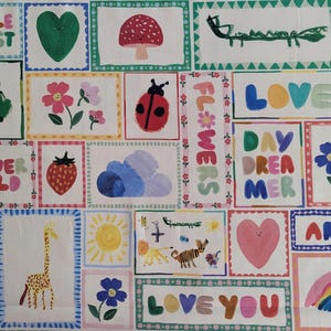 May include: A colorful fabric with a patchwork design featuring various illustrations, including a frog, a ladybug, a mushroom, a heart, a giraffe, a rainbow, a cloud, a sun, and flowers. The fabric also includes the words "Little Artist", "Flower Child", "Dreamer", "Flowers", "Love", "Day Dreamer", "Love You", and "Artist".