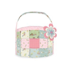 May include: A pink and green patchwork fabric storage basket with a flower-shaped handle. The basket is made of quilted fabric and has a floral pattern.