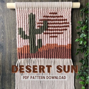 May include: A wall hanging made with macrame techniques, featuring a geometric design of a cactus and a sun in shades of pink, orange, brown, and green. The text "DESERT SUN PDF PATTERN DOWNLOAD" is printed below the design.