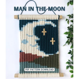 Op de afbeelding: Een wandhanger gemaakt met macramé touw in een geometrisch patroon. Het patroon heeft een blauwe halve maan met twee gouden sterren. De tekst "MAN IN THE MOON" staat bovenaan de afbeelding. De tekst "PDF PATTERN DOWNLOAD" staat onderaan de afbeelding.