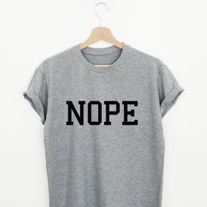 May include: A gray t-shirt with the word "NOPE" printed in black block letters.
