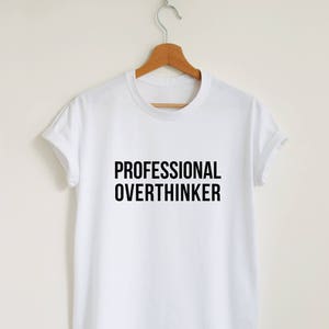 Pode incluir: Camiseta branca com texto preto que diz "PROFESSIONAL OVERTHINKER"