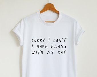 May include: White t-shirt with black text that reads "Sorry I can't I have plans with my cat."