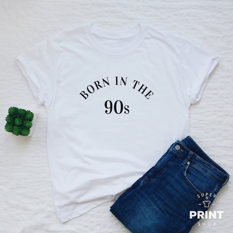 May include: White t-shirt with black text that reads "Born in the 90s".