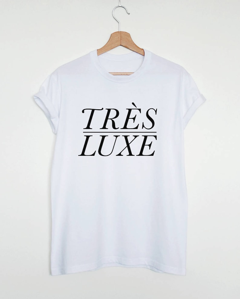 May include: White t-shirt with black text that reads "TR&Egrave;S LUXE" in a stylized font.