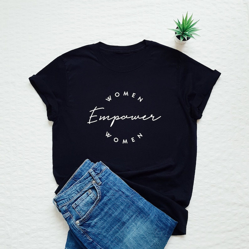 May include: Black t-shirt with white text that reads "Women Empower Women" in a circle.