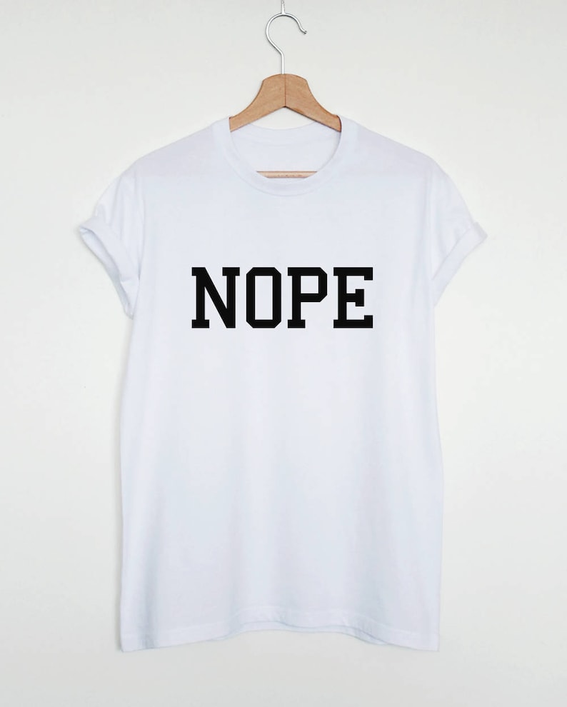 May include: White t-shirt with black text that says "NOPE" in a bold, blocky font.