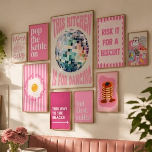 Puede incluir: Una pared de galería con nueve láminas rectangulares en tonos rosas, que incluye un gráfico de bola de discoteca con el texto THIS KITCHEN IS FOR DANCING, un huevo frito, una pila de tortitas y varias frases como POP THE KETTLE ON y RISK IT FOR A BISCUIT.