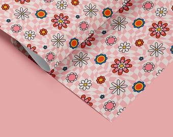 May include: Pink wrapping paper with a repeating pattern of white daisies and red, pink, and blue flowers on a checkered background.