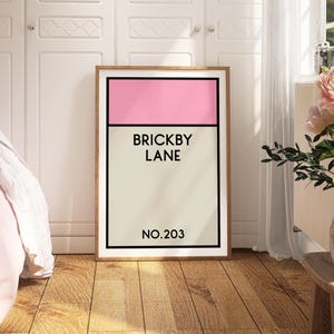 May include: A framed print with a pink and beige color scheme. The print features the text "Brickby Lane" and "No. 203".