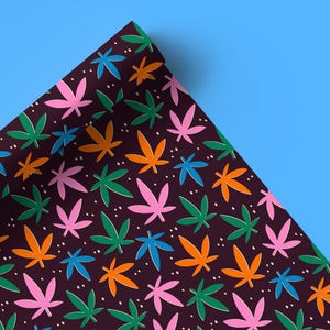 Pode incluir: Um fundo marrom escuro com um padrão repetido de folhas de cannabis coloridas. As folhas são em tons de rosa, laranja, verde e azul.