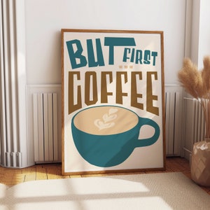 May include: A framed print with the text "But first, coffee" in brown letters. A teal mug with a beige coffee drink and latte art is below the text.