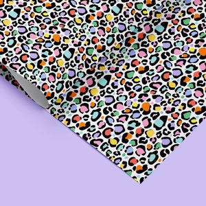 May include: A white background with a repeating pattern of colourful leopard spots. The spots are in shades of pink, orange, yellow, green, blue, and purple.