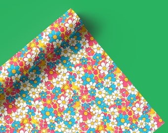 May include: A corner of colorful floral wrapping paper with a yellow, white, pink, and blue daisy pattern. The paper is folded over on itself, creating a triangular shape.
