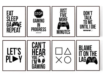 May include: Eight black and white printable wall art prints with gaming-themed text and graphics. The prints feature phrases like "Eat Sleep Game Repeat", "Stop Gaming in Progress", "Just Five More Minutes", "Don't Talk to Me Until I Die", "Let's Play", "Can't Hear You I'm Gaming", "Blame it on the Lag", and a set of controller buttons.