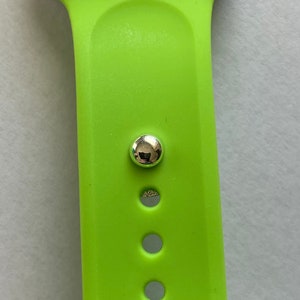 May include: A lime green Apple Watch band with a silver buckle and five holes for adjusting the fit.