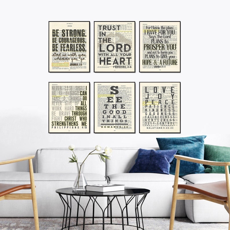 May include: Six black framed prints with white backgrounds and black text. The prints feature bible verses and inspirational quotes. The prints are arranged in two rows of three. The prints are hanging on a white wall above a couch.