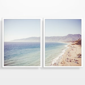 May include: A split-view image of a beach scene. The left side shows a wide shot of the ocean with a hazy mountain range in the distance. The right side shows a beach with people on the sand and in the water. The ocean is a light blue color and the sand is a light brown color.